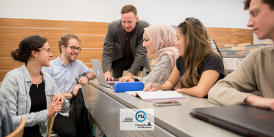 Un chargé de cours intéragit avec ses étudiants et ses étudiantes en classe.