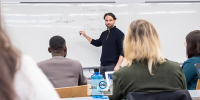 Un enseignant fait une démonstration au tableau à ses étudiants et étudiantes.